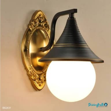 A wall-mounted light fixture featuring an ornate golden oval backplate, a curved matte black arm, a ribbed conical black shade with gold accent bands, and a spherical white glass diffuser. — 3D model