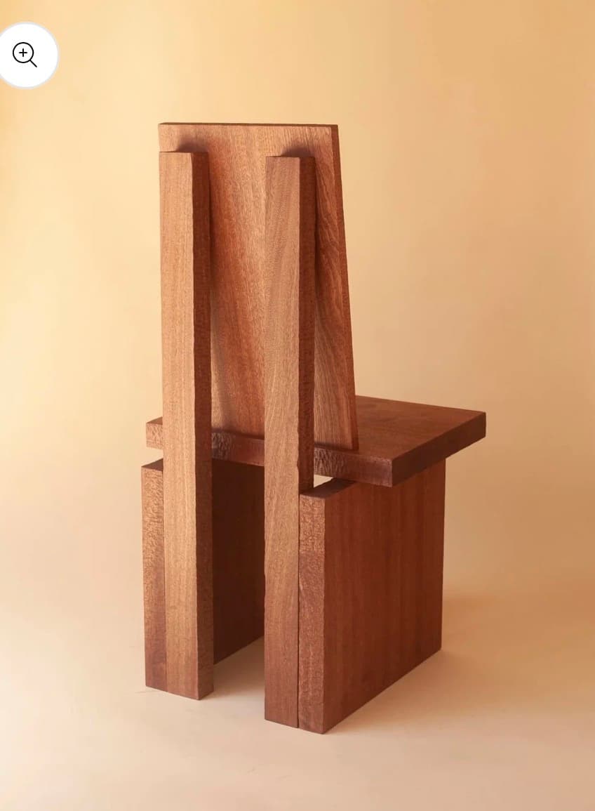 A sculptural chair crafted entirely from solid wood planks, featuring a minimalist and brutalist design with a dark reddish-brown finish. — 3D model