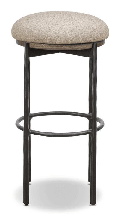 A bar stool featuring a round, upholstered seat made from a light beige, textured fabric, supported by a dark-stained wooden rim. The base consists of four dark, possibly forged or cast metal legs with an uneven, textured surface, connected by a circular metal footrest for stability and comfort. The overall aesthetic combines rustic and industrial elements. — 3D model