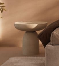 A light gray or off-white modern cylindrical pedestal accent table featuring a round, slightly dished top and a sturdy, monolithic base. — 3D model