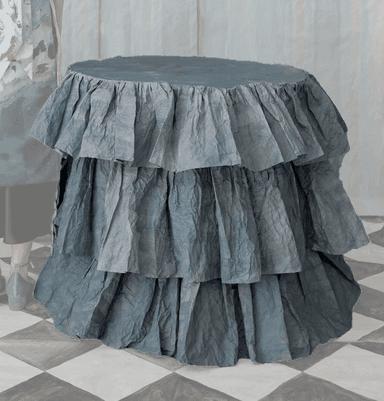 A cylindrical accent table entirely covered in multiple tiers of ruffled, crumpled blue-grey fabric, presenting a soft and textural appearance. — 3D model