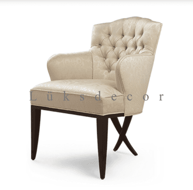 An elegant, cream-colored upholstered armchair featuring classic design elements. The chair has a gently curved, scalloped backrest adorned with deep button tufting. Its armrests are fully upholstered, providing a comfortable feel. The seat is also upholstered in the same patterned cream fabric. The chair is supported by four dark wood tapered legs, with the front two legs connected by a distinctive X-shaped stretcher near the floor. — 3D model