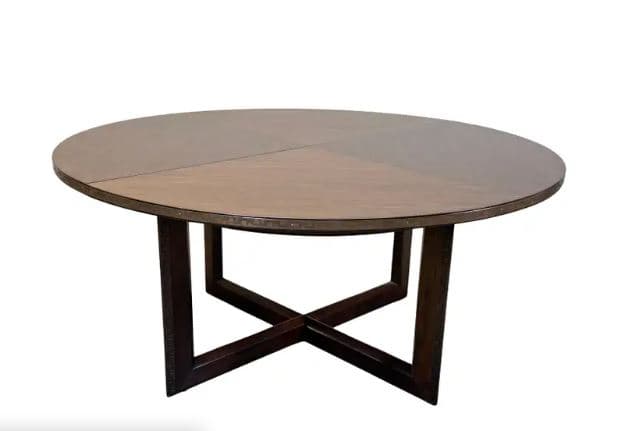 A round dining table featuring a dark wood finish and a distinctive cross-style base. The table top appears to be constructed from multiple segments, suggesting it might be an extendable design. The base consists of four substantial vertical legs connected by two intersecting horizontal beams, forming an 'X' shape. The overall aesthetic is sturdy and contemporary. — 3D model