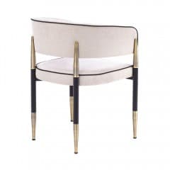 A contemporary upholstered armchair featuring a curved barrel back and seat, covered in a light beige textured fabric with distinct black piping. The chair is supported by a black metal frame with elegant brass accents on the integrated armrests and tapered leg tips. — 3D model
