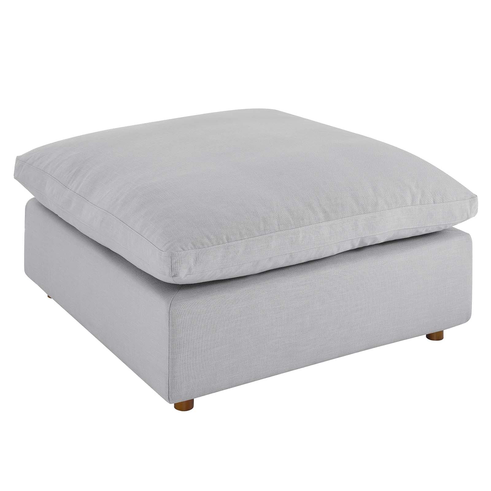 A modern, square-shaped ottoman featuring a light gray, linen-look fabric upholstery. It consists of a plush, oversized top cushion resting on a slightly smaller, more rigid base, supported by small, subtly splayed wooden feet. — 3D model