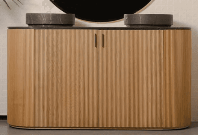 A modern double bathroom vanity featuring a cabinet with a fluted light wood finish and a dark, marble-patterned countertop with two integrated circular stone basins. The cabinet has rounded ends and two small gold-toned handles. — 3D model