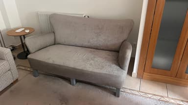 A two-seater sofa with a curved back and armrests. The upholstery appears to be a textured fabric with a subtle distressed pattern. The legs are angular and support the sofa from underneath. — 3D model