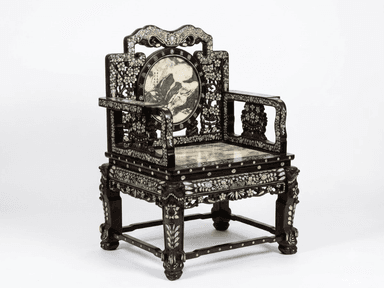 An antique East Asian armchair featuring a dark, carved hardwood frame extensively inlaid with iridescent mother-of-pearl. The chair has a square, polished marble seat with green and white veining. The backrest is ornate, topped with a shaped crest rail and a central circular panel depicting a landscape scene. The armrests and legs are also heavily decorated with floral and geometric mother-of-pearl inlay and intricate carving. — 3D model