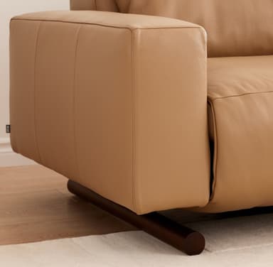A modern two-seater reclining sofa, upholstered in smooth, light tan leather. It features two individual seats, each with a plush back cushion and integrated armrests. The sofa stands on small, dark-colored cylindrical feet, offering a minimalist profile. — 3D model