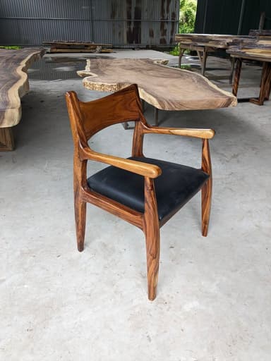 A Mid-Century Modern style dining armchair crafted from rich, dark wood with a distinct grain, featuring a contoured, integrated backrest and armrests, and an upholstered black leather seat. The chair's design emphasizes organic curves and sculpted lines. — 3D model