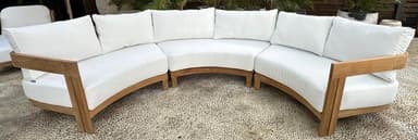 A modular outdoor sectional sofa with a curved design, featuring a wooden frame and white upholstered cushions and backrests. The sofa is composed of multiple curved sections connected to form a semi-circular arrangement. — 3D model