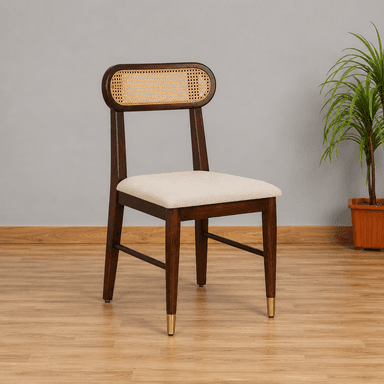 A contemporary dining chair featuring a dark stained wooden frame, a distinctive oval-shaped backrest with natural cane webbing, and a light beige upholstered seat. The chair's tapered legs are accented with brass ferrules on the front two feet. — 3D model