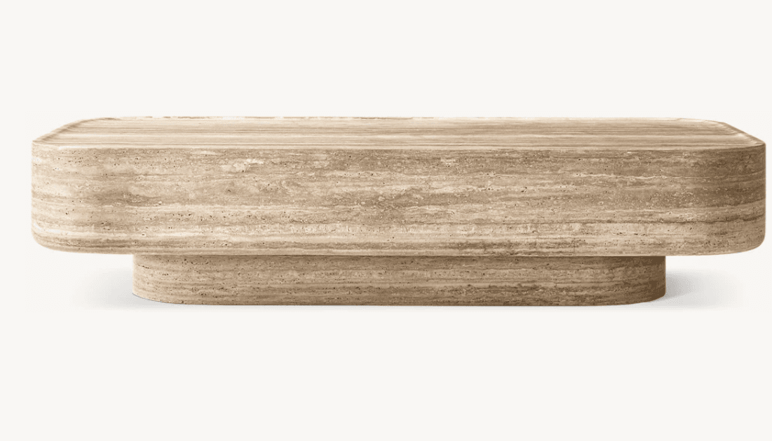 A low-profile coffee table crafted entirely from light brown travertine stone, featuring an elongated rectangular top with softened, rounded corners. The top rests upon a slightly smaller, solid plinth base of similar shape, creating a monolithic and grounded aesthetic. The natural striations, veins, and porous texture characteristic of travertine are visible across all surfaces, highlighting the material's organic beauty. — 3D model