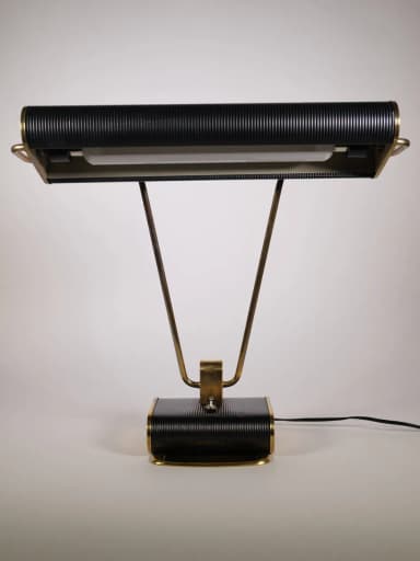 A stylish mid-century industrial desk lamp featuring a horizontal, rectangular, ribbed black shade and a matching ribbed black rectangular base. It is supported by two V-shaped polished brass arms that connect the shade to the base, with a central brass accent bracket. — 3D model