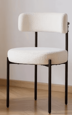 A modern accent chair with a black metal frame and a plush, textured cream-colored upholstery. The seat is round and thickly padded, and the backrest is a gently curved, low profile with a cylindrical armrest integrated into one side. The legs are slim and angled. — 3D model