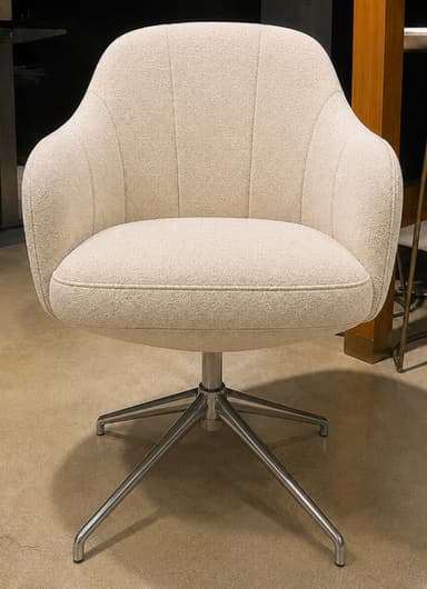An upholstered armchair with a rounded, shell-like form, integrated armrests, and a fluted back. It features a swivel mechanism and a polished metal four-star base with splayed legs. The upholstery is a light beige, subtly patterned fabric. — 3D model