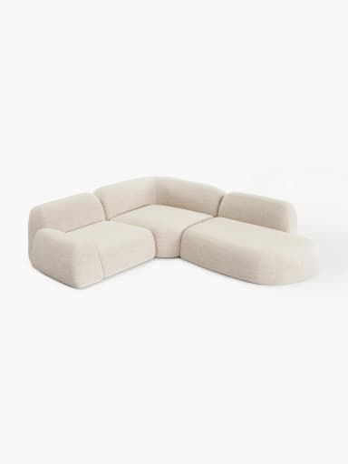 A contemporary modular sectional sofa featuring soft, rounded forms and upholstered in a light-colored, textured fabric. The configuration includes a two-seat section, a corner piece, and an integrated ottoman/chaise extension, creating an L-shaped layout with a low profile. — 3D model