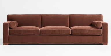 A contemporary three-seater sofa upholstered in a rich terracotta-brown velvet fabric. It features clean track arms, three plush seat cushions, and three matching back cushions, all detailed with subtle piping. Two cylindrical bolster pillows are included, one at each end, and the sofa rests on low-profile, recessed feet. — 3D model