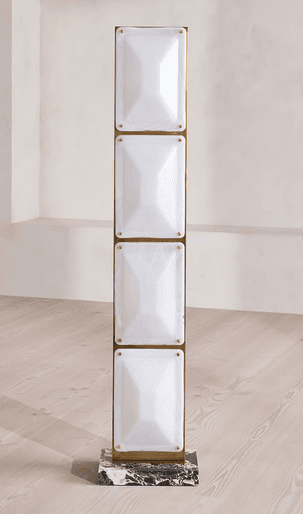 A tall, slender floor lamp featuring a brass-toned metal frame with four vertically stacked, rectangular light panels. The panels are made of frosted white glass or acrylic, each with a pyramidal or faceted surface. The lamp is supported by a rectangular base made of black and white marbled stone. — 3D model