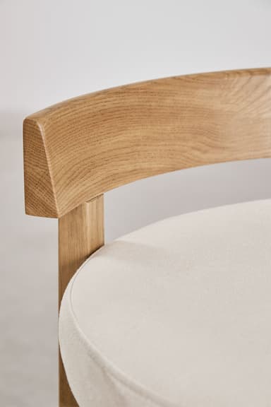 A modern bar stool featuring a light-toned oak wood frame and a circular cream upholstered seat. It has a low, gently curved backrest and a square-profile leg structure with an X-shaped cross-brace footrest. — 3D model