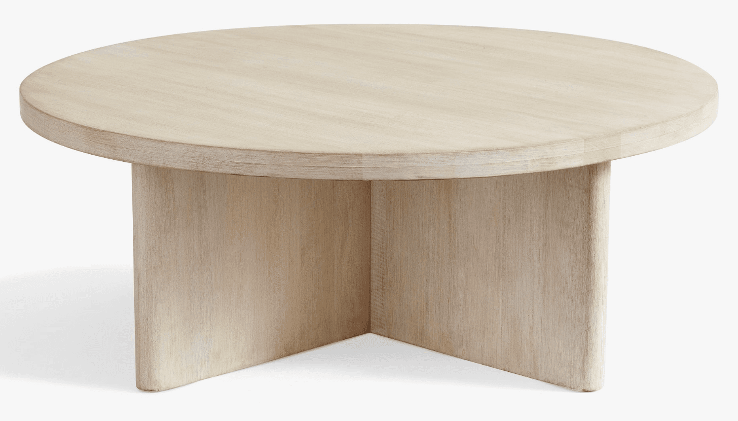 A round, low-profile coffee table crafted from light-colored, bleached wood. Its design features a thick circular top supported by a substantial, sculptural base composed of three intersecting flat panels. — 3D model