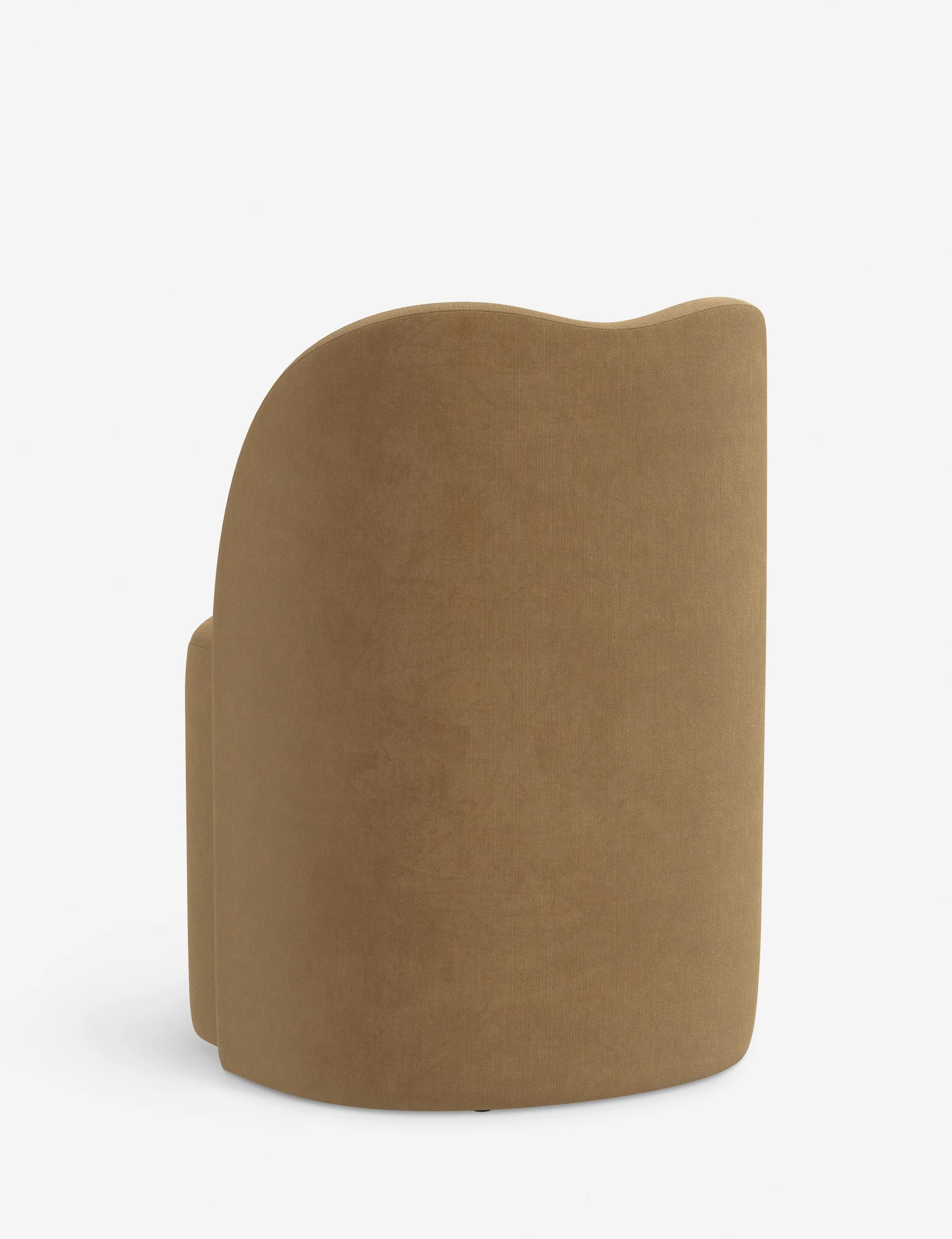 The item is a single-seater upholstered chair with a continuous, gently curved back and integrated armrests, creating a semi-enclosed, inviting form. It is covered in a camel or brownish-beige textured fabric, likely a woven textile. The base is not visible, suggesting a fully upholstered design extending to the floor or very low, concealed legs. — 3D model