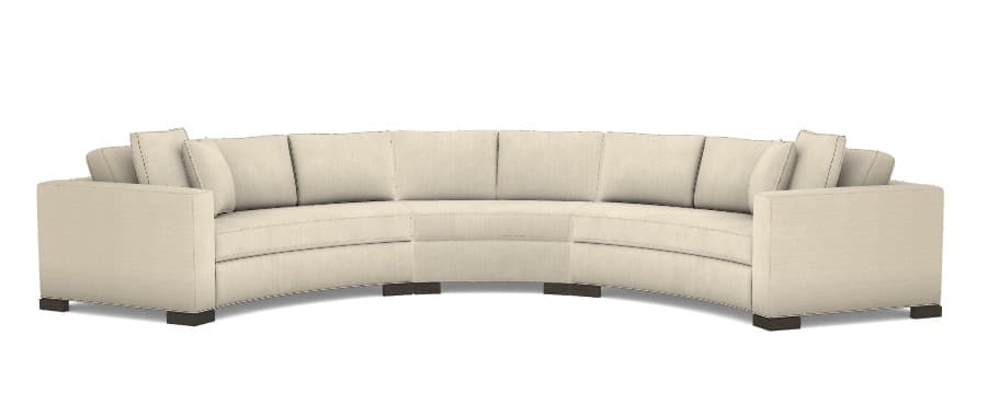 A contemporary, generously sized curved sectional sofa, upholstered in a light-colored, possibly off-white or beige, textured fabric. The sofa features a sweeping, semicircular form with wide, flat arms and five distinct seating sections. Each section has a loose seat cushion and a loose back cushion, accompanied by additional throw pillows at the ends. The sofa rests on dark, low-profile block feet, contributing to a clean, modern aesthetic. — 3D model