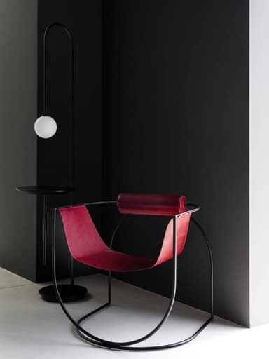 A contemporary rocking lounge chair featuring a continuous black tubular metal frame and a deep, burgundy leather sling seat. The frame forms the rocking base and supports a single cylindrical leather-wrapped armrest. — 3D model
