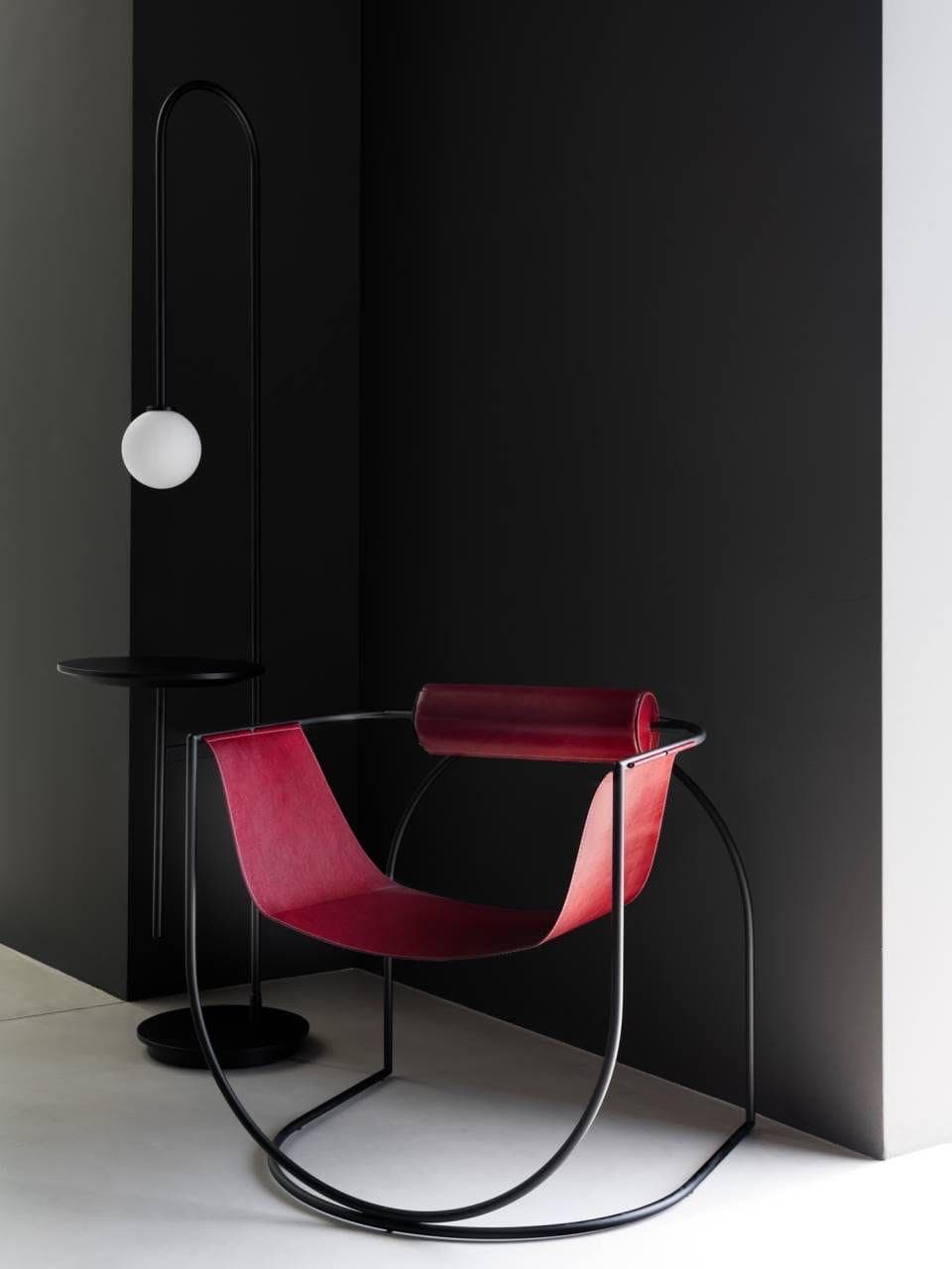 A contemporary rocking lounge chair featuring a continuous black tubular metal frame and a deep, burgundy leather sling seat. The frame forms the rocking base and supports a single cylindrical leather-wrapped armrest. — 3D model