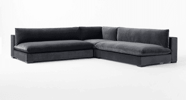 A deep-seated, modular sectional sofa with a low profile and plush cushioning. The sofa features a dark gray, velvet-like upholstery and a clean-lined, contemporary design. It is configured in an L-shape, suggesting a chaise lounge component on the right side. — 3D model