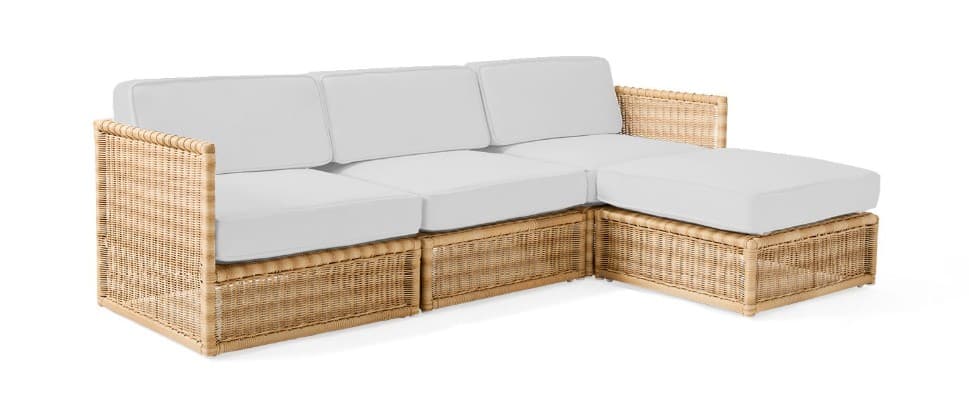 A natural-toned, L-shaped sectional sofa with white cushions, featuring a woven rattan frame and an integrated chaise lounge. — 3D model