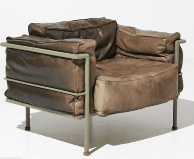 A contemporary armchair featuring a tubular metal frame and plush, overstuffed leather cushions. The frame has a matte green finish and supports the seat, back, and armrest cushions. The leather appears to be distressed or aged, with variations in color and texture. The armchair has a low profile and appears designed for comfort. — 3D model