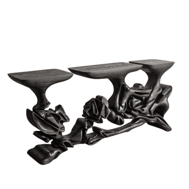 A highly sculptural console table featuring a dark, almost black, wood finish. It comprises three distinct, irregularly shaped flat display surfaces supported by an intricate, organically formed base that evokes draped fabric or fluid natural structures. The wood grain is visible through the dark finish, adding texture to its complex form. — 3D model