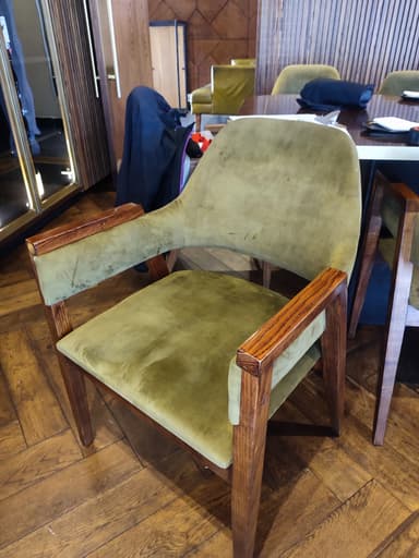 A mid-century modern armchair with a wooden frame and upholstered seat, back, and armrests. The frame is constructed from dark wood, and the upholstery is a textured olive green fabric. The chair features slightly tapered legs and armrests that are integrated into the wooden frame. — 3D model