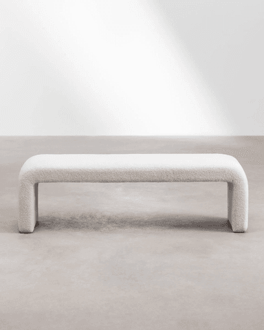 A cream-colored, bouclé upholstered bench with a rounded, continuous form. The bench has a singular, sculptural design where the seat and legs are integrated into a unified U-shape, creating a modern and minimalist aesthetic. — 3D model