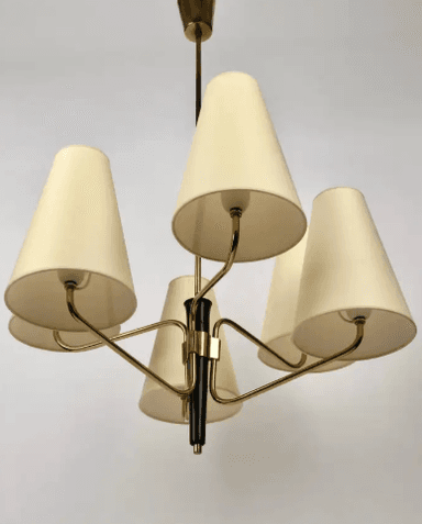A vintage Mid-Century Modern chandelier featuring a central brass stem descending from a ceiling canopy. Six radiating arms, also in brass, extend outwards, each terminating in an upward-pointing, conical, off-white fabric shade. The central column has a prominent black accent piece, providing a striking contrast to the brass finish. The design is characteristic of the 1950s to 1960s, emphasizing clean lines and functional elegance. — 3D model