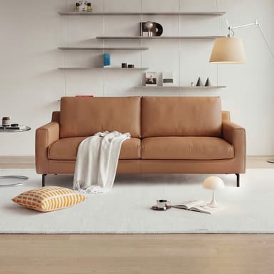 A modern two-seater sofa upholstered in tan leather, featuring clean lines, square armrests, and a low profile. It has two loose seat cushions and two loose back cushions, supported by slender, tapered black metal legs. A white throw blanket is draped over one armrest and cushion. — 3D model