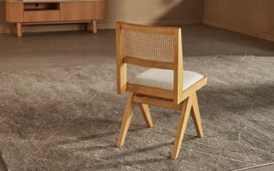 A modern dining chair with a minimalist design, featuring a wooden frame and a cushioned seat. The chair has a unique angular leg structure and a slightly reclined backrest. — 3D model