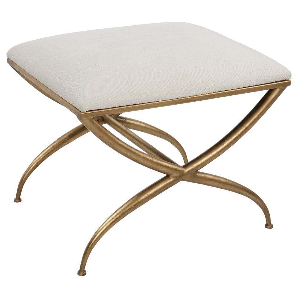A square, upholstered ottoman featuring a light, neutral-toned fabric top and a decorative, X-shaped antique brass metal base with gracefully curved legs. — 3D model