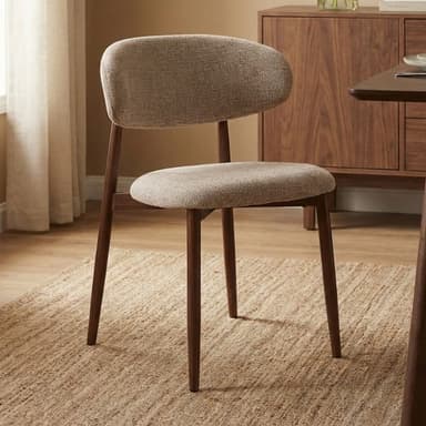 An armless dining chair featuring light beige textured fabric upholstery on both the seat and a distinct, curved backrest. The chair is supported by four dark brown, slender, tapered wooden legs. — 3D model