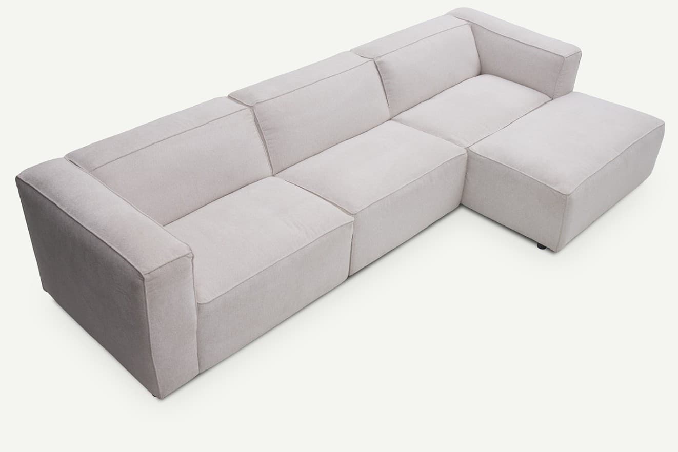 A light beige modular L-shaped sectional sofa with a chaise lounge. The sofa features clean lines, block-style arms, and thick, comfortable cushions. It is upholstered in a textured fabric and rests on discreet, low-profile feet, creating a modern and minimalist aesthetic. — 3D model