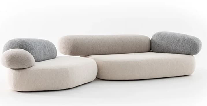 A modular sectional sofa with rounded, organic forms, resembling pebbles or stones. The sofa features a low profile with deep seating. The upholstery appears to be a textured fabric, possibly wool or felt, in contrasting neutral tones of light beige and grey. The backrests and armrests are separate, rounded cushions that can be positioned in various configurations, contributing to its modern and playful design. — 3D model