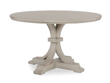 A round pedestal dining table with a light-colored finish. The table features a thick, banded tabletop with a subtle beveled edge. The pedestal base consists of a central square column from which four curved supports fan out, connecting to a wider, rectangular base with decorative moldings. The overall design suggests a transitional or modern farmhouse style. — 3D model