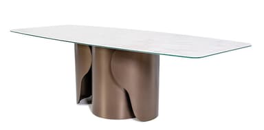 A modern dining table with a rectangular, subtly rounded countertop supported by a unique, sculptural pedestal base. The base consists of two curved, cylindrical elements that interlock and create an abstract, flowing form. The tabletop appears to be made of a light-colored, veined material, possibly marble or a high-quality laminate, with a clear glass overlay. The base has a metallic finish in a warm, bronze tone. — 3D model