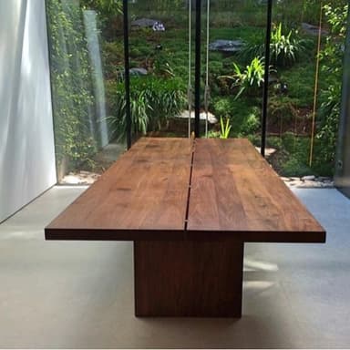 A modern, rectangular conference table featuring a dark wood finish, likely walnut veneer, with a panelled tabletop design. The table is supported by a solid block-style pedestal base, giving it a minimalist and contemporary appearance. The tabletop appears to be constructed from multiple distinct sections, creating subtle seams across its surface. The overall form factor is elongated and robust, designed for professional meeting environments. — 3D model