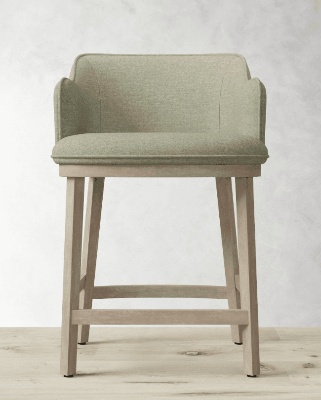 A modern bar stool with a upholstered seat and back, featuring gently curved armrests. The base consists of four wooden legs connected by stretchers for stability. The seat and back are upholstered in a textured fabric, and the wooden frame has a light, weathered finish. — 3D model