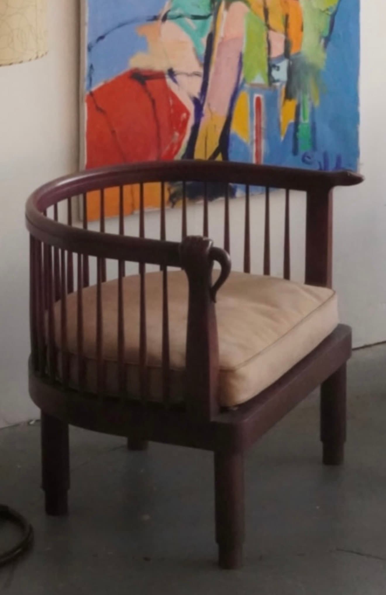 An armchair featuring a dark brown, possibly mahogany or walnut stained wooden frame, with a distinctive barrel-shaped backrest and armrests. The backrest is composed of vertical wooden spindles, while the armrests are solid and curved. It includes a loose, light beige upholstered seat cushion, and stands on four sturdy, tapered legs. — 3D model