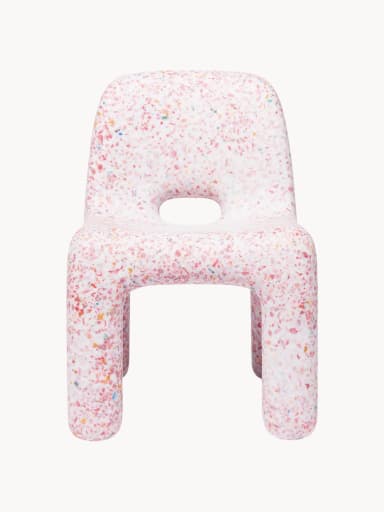A small, child-sized chair made entirely from a single molded piece of recycled plastic, featuring a distinctive speckled or confetti-like pattern. The chair is predominantly white with multi-colored fragments (red, orange, yellow, blue, green) embedded throughout the material. It has a simple, monolithic design with rounded edges and a backrest, and an oval cutout in the seat. — 3D model