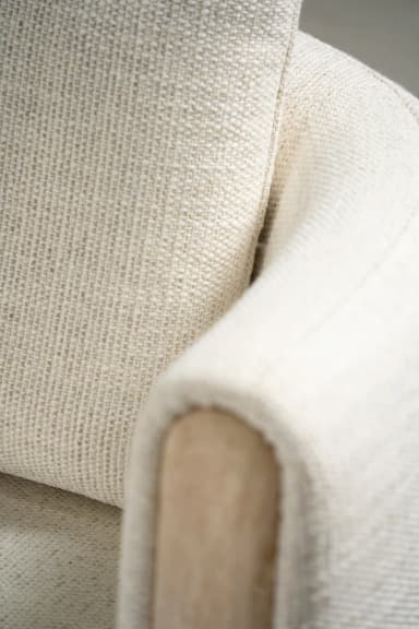 A large, curved sectional sofa upholstered in a light, textured boucle fabric, featuring a left-hand chaise extension and a unique right-hand armrest with a recessed wooden panel. The sofa includes several matching decorative pillows, both square and round. — 3D model