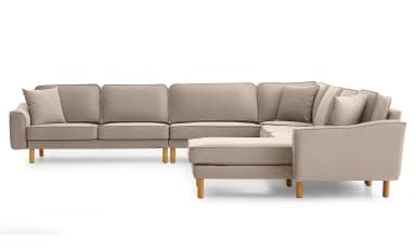 A modern L-shaped sectional sofa upholstered in a light beige or taupe fabric, featuring a right-hand facing chaise lounge. The sofa has a low-profile design with clean lines, track arms, and exposed wooden legs. Each cushion features piped edge detailing, and multiple throw pillows are included. — 3D model
